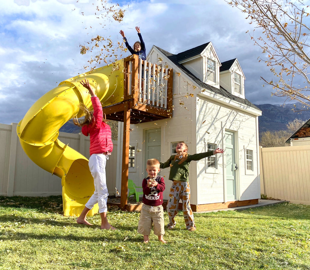 Kids jumping near a white playhouse with slide