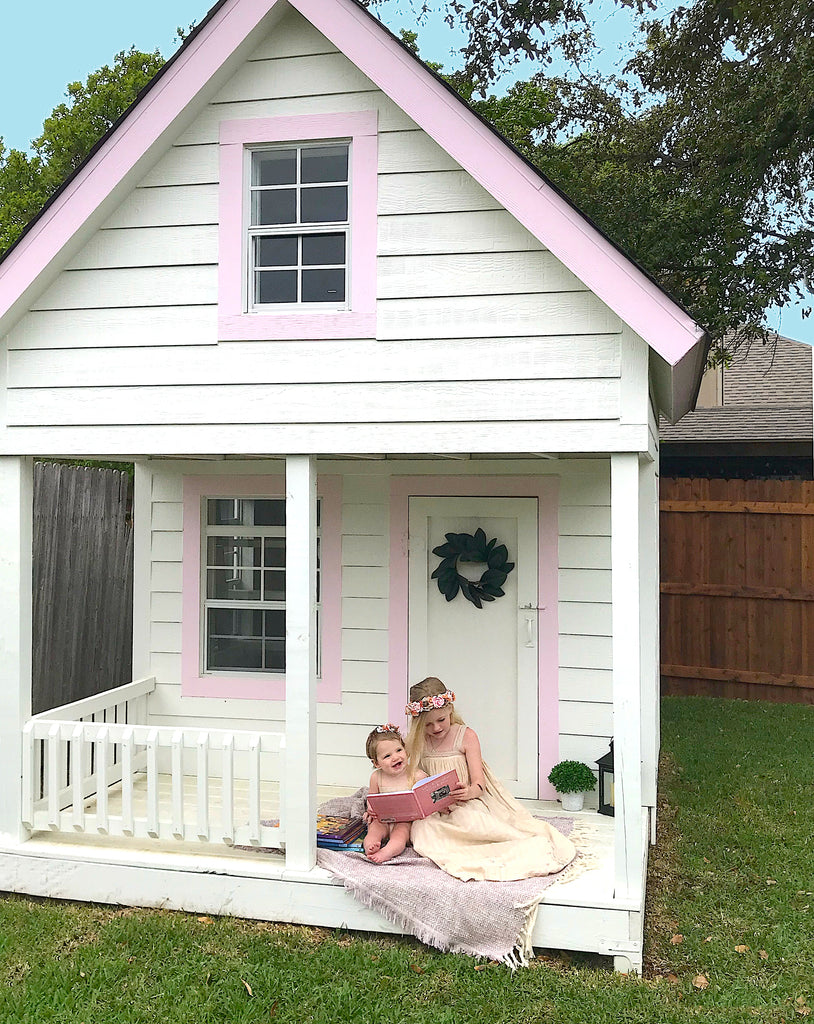 2 girls sitting on deck of white and pink loft playhouse