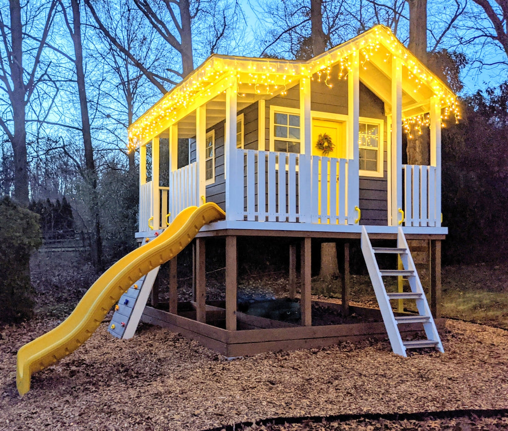 2 story playhouse with Christmas lights and wrap around porch