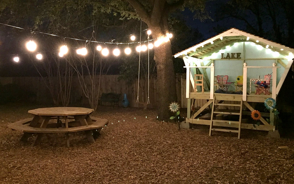 Cozy open, elevated playhouse with lights at night