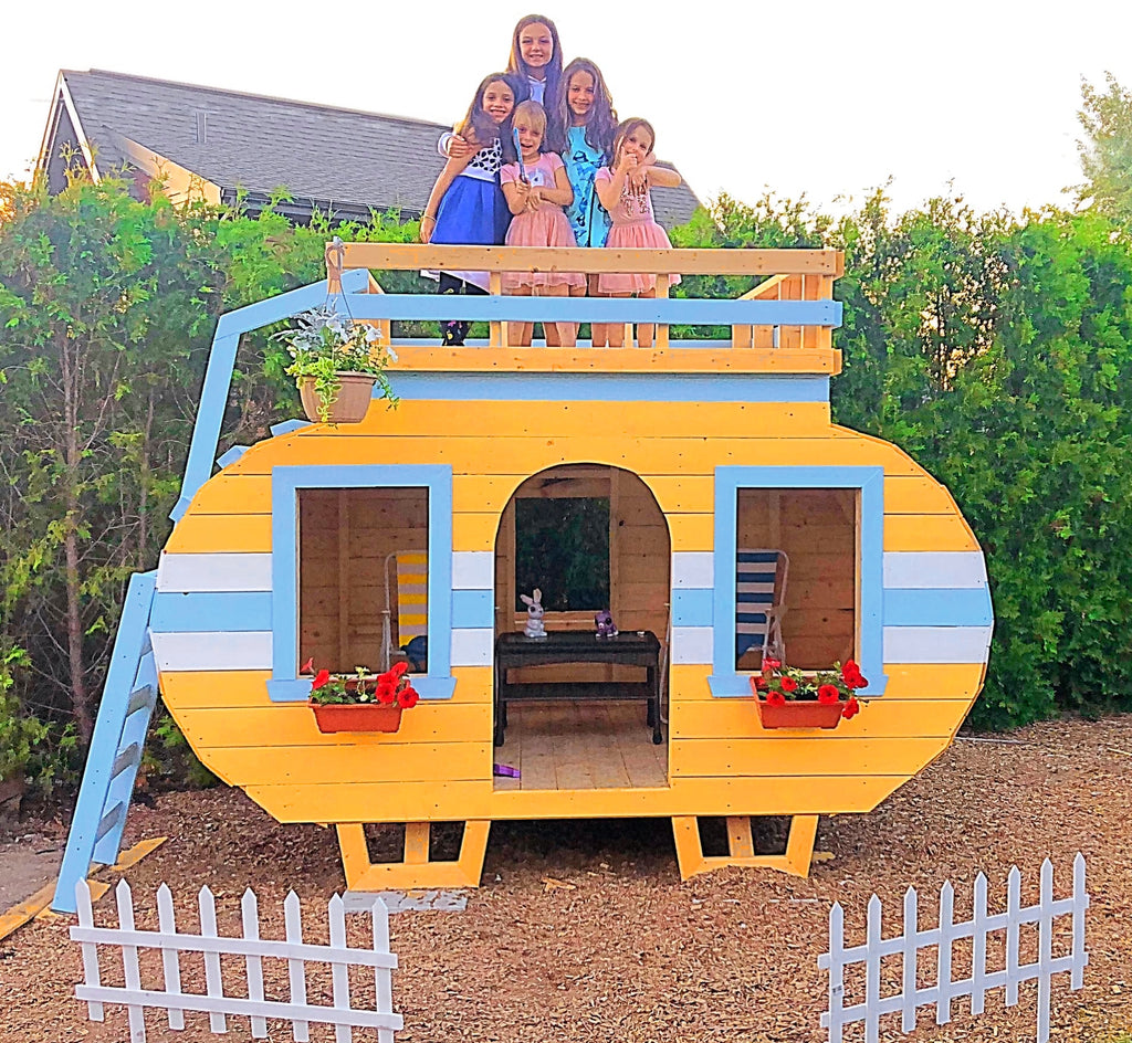 Girls playing on yellow camper playset with loft and flowerboxes