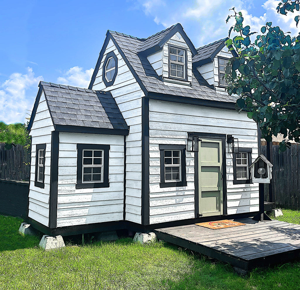 White and block, colonial style playhouse with dormers and shiplap siding