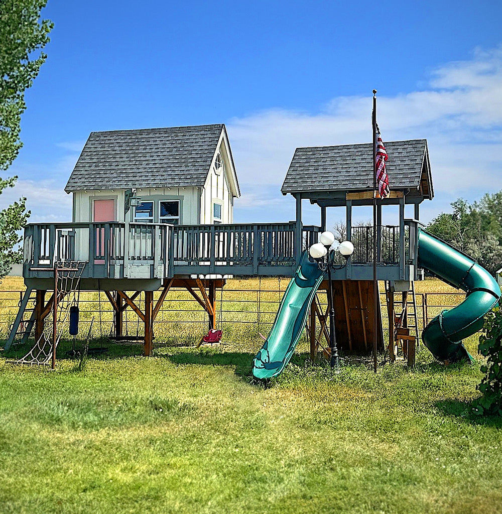 Cute children's elevated playhouse and playground with slides and a on stilts under a clear blue sky.