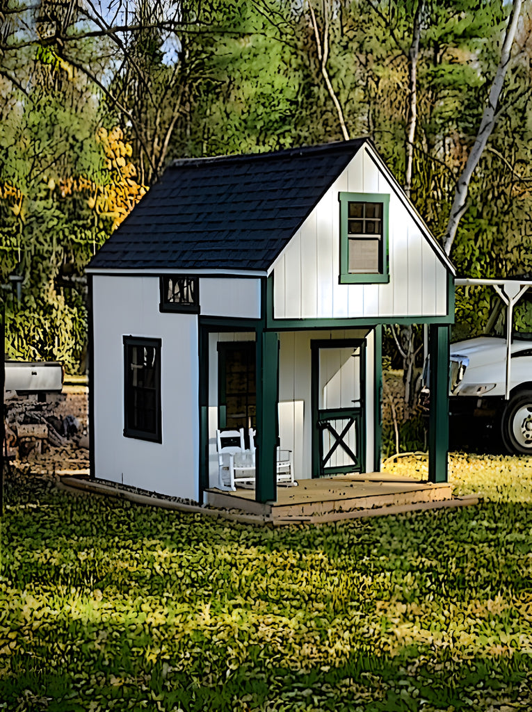 Small white playhouse with green trim in a grassy area with trees in the background