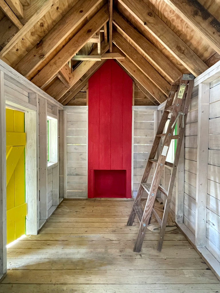 Inside view of log cabin playhouse with fireplace and ladder