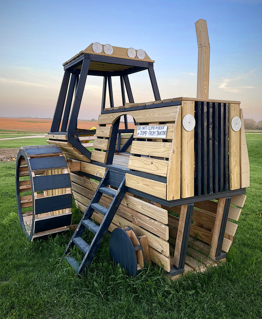 Wooden tractor playset on a grassy field with a clear sky