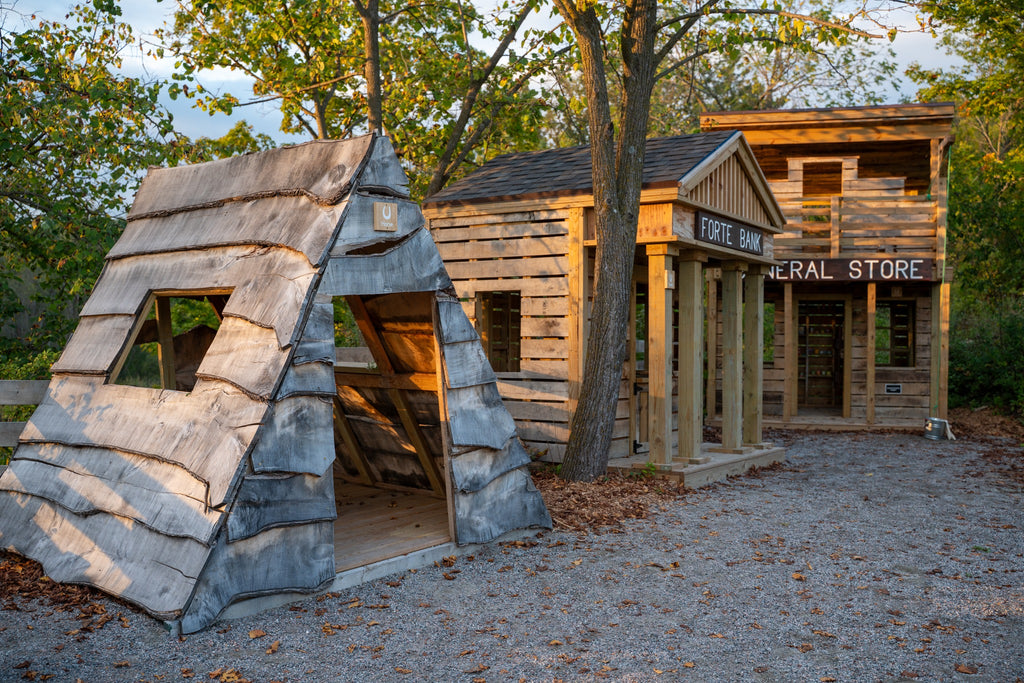 Wooden play structure resembling a fort and a store in a natural setting