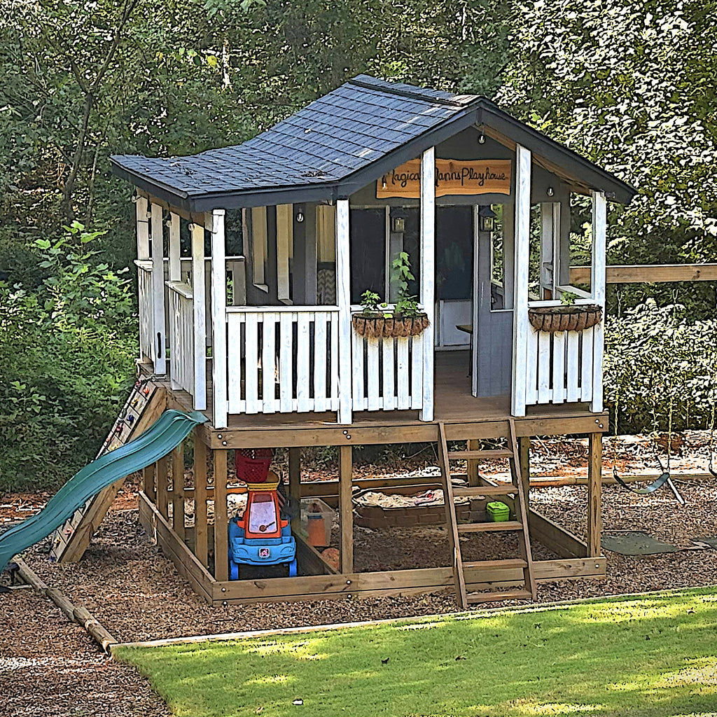 Wooden, elevated playhouse with wrap around porch, rockwall, slide, swingset and rustic look.
