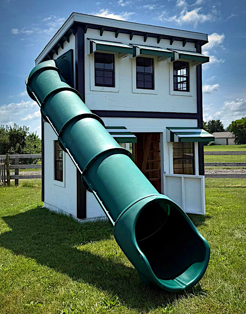 Market themed playhouse with a green slide on a grassy area under a blue sky.