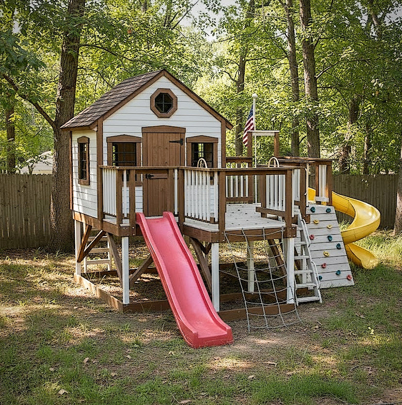 Wooden playhouse with a red slide and yellow climbing wall in a backyard setting.