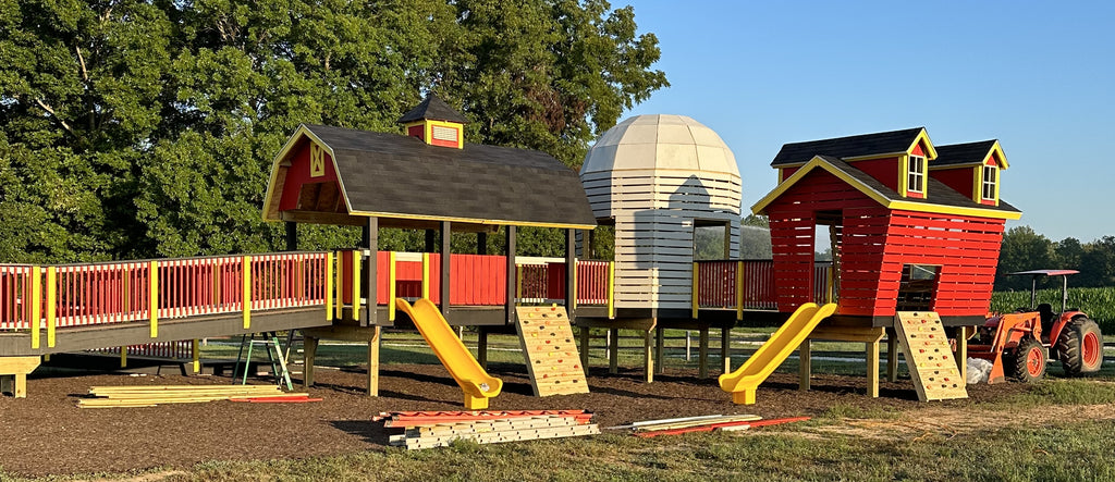 Elevated farm themed playground with barn, silo and corn crib play structures