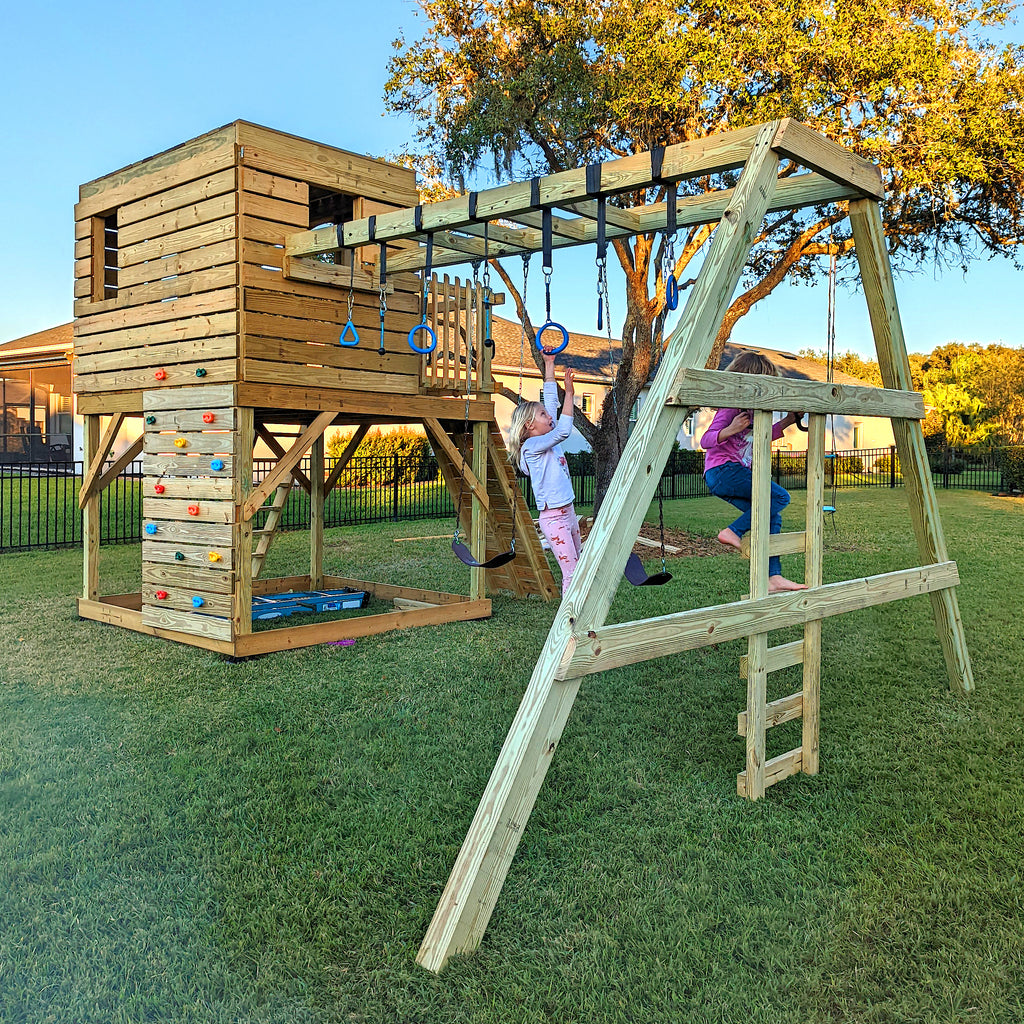 girls playing on their backyard clubhouse and swingset