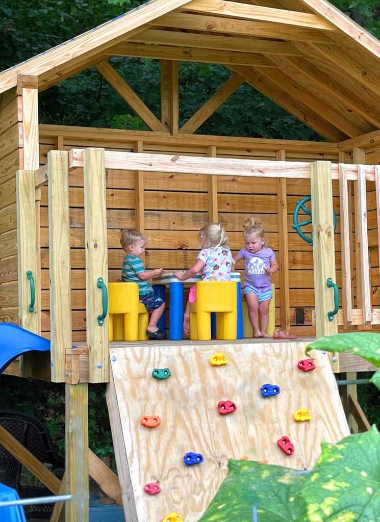 Three toddlers playing on their open, elevated clubhouse