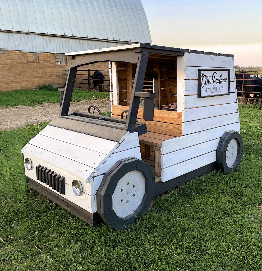 Outdoor, white wooden van playset for kids at a farm.
