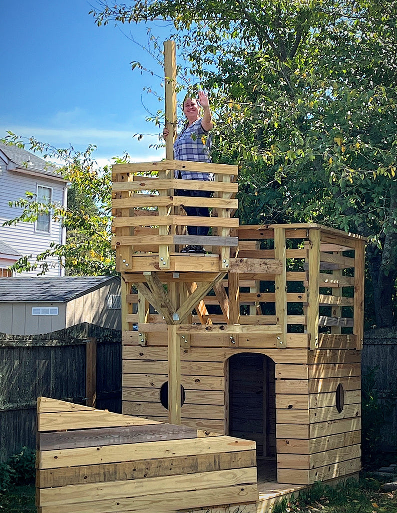 Wooden backyard pirate ship with woman waving in the crow's nest.