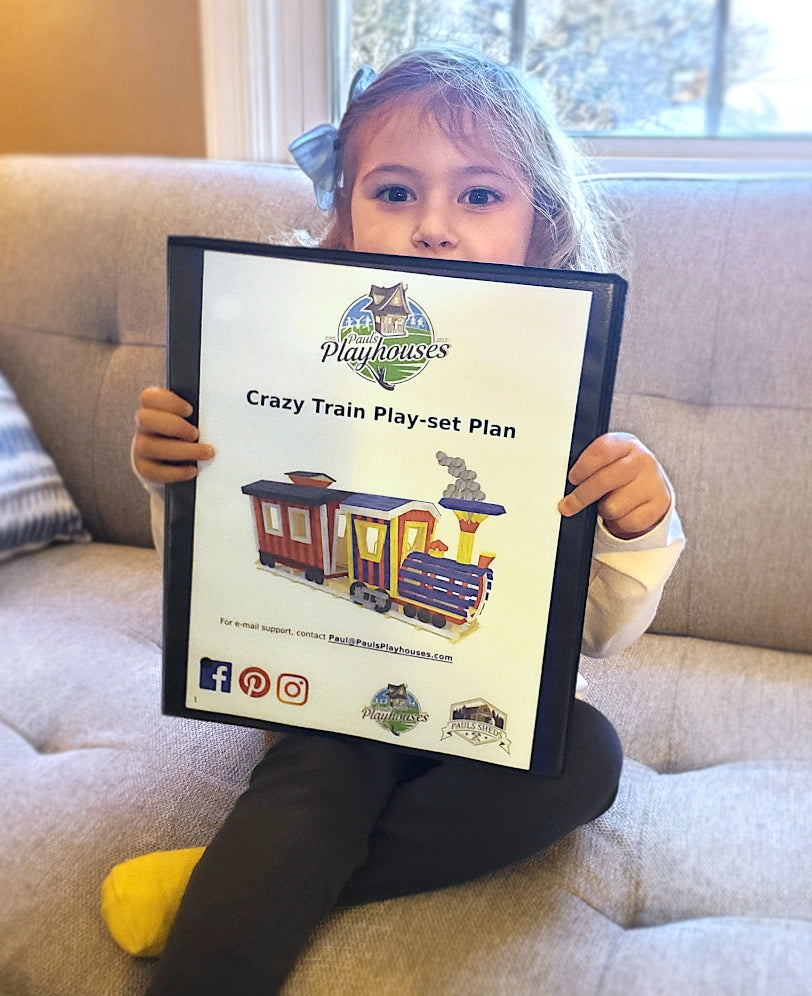 Girl holding printed train playset plan on couch