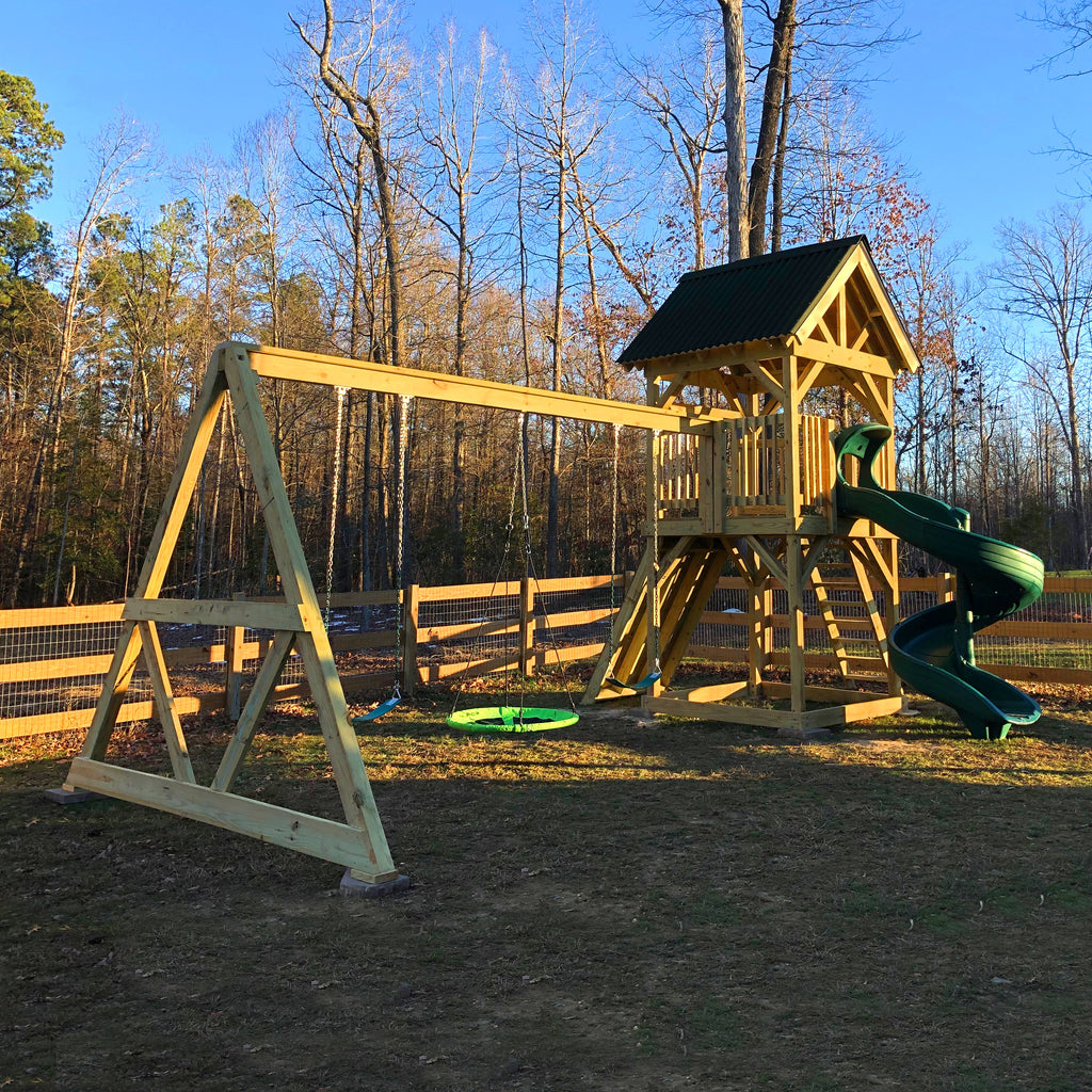 small, elevated playset with gable roof, spiral slide and attached swingset