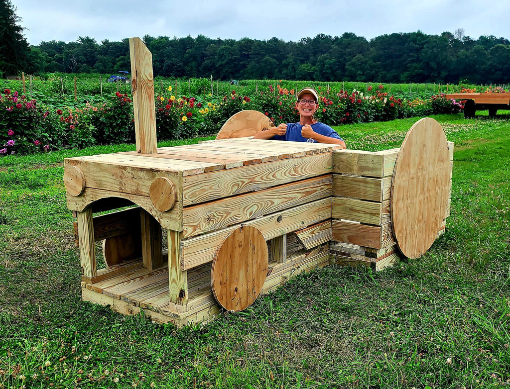 Woman driving wooden tractor playset on farm