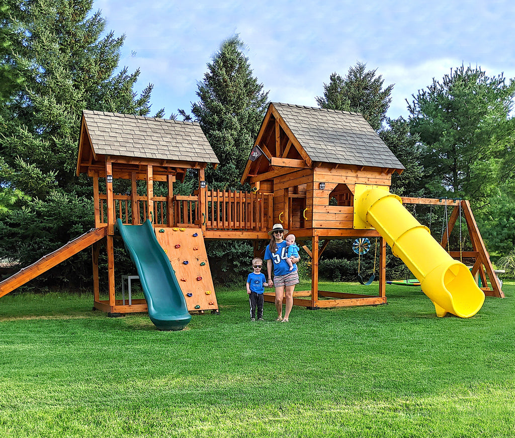 Family standing in front of stained, large playset