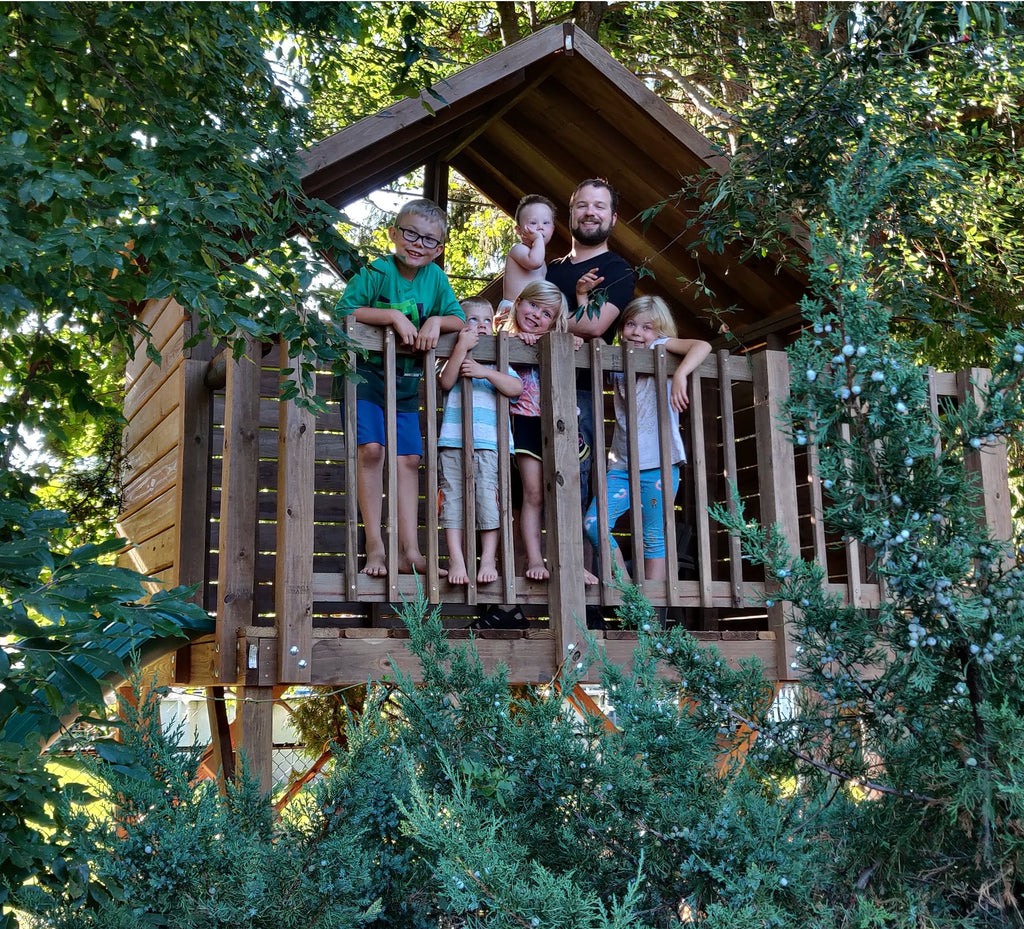 Family inside of their open gable playset in backyard
