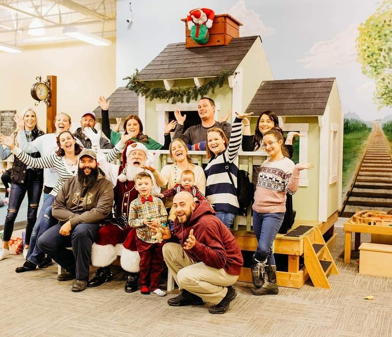 Group of people and Santa in front of indoor DIY train playset