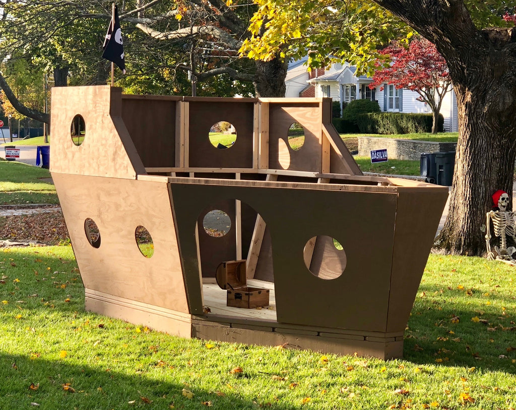 A small, wooden pirate ship in a front yard