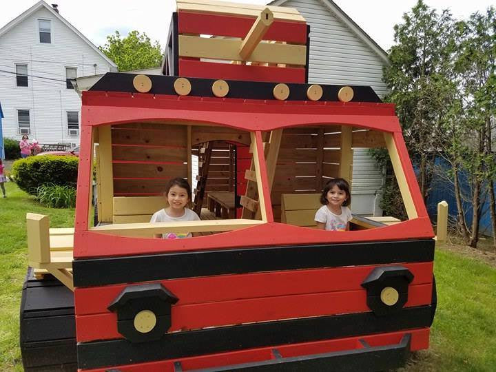 girls playing inside wooden firetruck playhouse